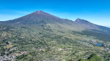Sembalun Vadisi 'nin üzerinde yükselen Rinjani Dağı' nın görkemli hava manzarası. Volkanik yamaçlar ve tarım alanları Lombok 'ta nefes kesici bir manzara yaratır..