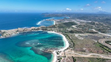 Lombok sahili manzarası yuvarlanan yeşil tepeler, dolambaçlı yollar ve sonsuz mavi okyanusla süpürülüyor. Macera ve tropikal rahatlama için mükemmel bir sahne..