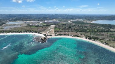 Parlak mavi ve yeşil tonlara sahip kristal berraklığında bir göl beyaz kumsalın mükemmel bir yayı ile buluşur. Lombok kırsalında virajlı yollar ve uzak tepeler var..