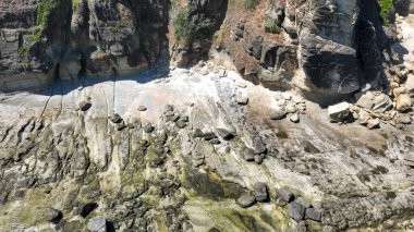 Yıpranmış kaya oluşumlarını ve Lombok kayalıklarının tabanındaki dağılmış kayaları kapatın. Gelgitin taşlardaki eski desenleri ortaya çıkardığı yer..
