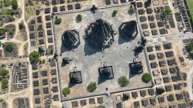 Prambanan Tapınağı kompleksinin yukarıdan aşağı havadan görünüşü yeşil yamalar ve tarihi taş temellerle çevrili antik Hindu tapınakları ve kalıntılarının çarpıcı simetrisini ortaya çıkarıyor..