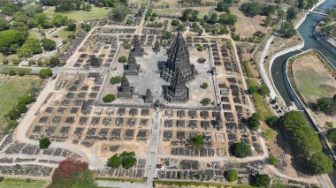 Prambanan Tapınağı 'nın havadan görünüşü, yeşil ağaçlar ve Orta Cava' nın huzurlu manzarasıyla çevrili harabelerin üzerinde yükselen antik taş kuleleri ortaya çıkarıyor..