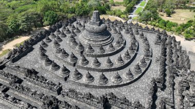 Borobudur görkemli üst terasları, çan şeklinde salyangozlar ve yükselen ana kubbeyle bezenmiş, yemyeşil, yüzyıllardır süren özveri ve sanatın somutlaştırılmış hali..