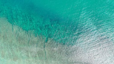 Havadan bakıldığında açık mavi denizden kumlu sığ sulara, hassas dokulara ve Lombok Adası yakınlarındaki yüzeyde ışıldayan ışığa canlı bir geçiş olduğu görülüyor..
