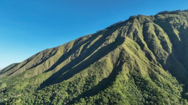 Güneş ışığı ve gölgelerin eşsiz hatları ve bu volkanik manzaranın vahşi güzelliğini ortaya çıkardığı Sembalun 'un sarp, yeşil tepelerinin yakın çekimi..