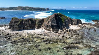 Lombok 'ta, temiz su ve okyanus esintisi ile çevrili gizli bir kumsal koyunun üzerinde görkemli kayalık uçurumlar yükseliyor..