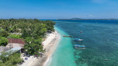 Su yüzeyinde tekneler var. Beyaz kumların, sallanan ağaçların ve gök mavisi suların rahatlama ve macera için mükemmel bir ortam yarattığı tropikal bir kıyı şeridinin sakin cazibesi..