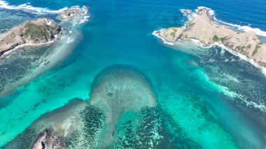 Lombok yakınlarındaki engebeli adalarla karşılaşan turkuaz suların ve mercan resiflerinin havadan görünüşü. Canlı deniz renkleri nefes kesici bir tropikal manzara yaratır. Keşif için mükemmel..