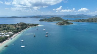 Gili Asahan yakınlarında demirlemiş yatları olan huzurlu bir körfez perspektifi. Avuç içi uzanan kıyılar ve zümrüt suları rüya gibi bir ada atmosferi sunar.