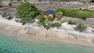 Gili Gede 'deki ahşap bir villanın havadan görünüşü büyük bir ağacın altına yerleştirilmiş, altın kum ve turkuaz su mükemmel bir tropikal kaçış yaratıyor..