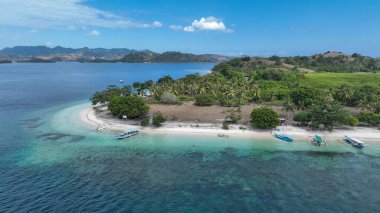 Kristal berraklığında bir göl, bu uzak ada cennetinde beyaz kumlu bir kıvrımla karşılaşır. Geleneksel tekneler kıyıya yakın süzülür, uzak tepeler ve ufukta mavi gökyüzü.