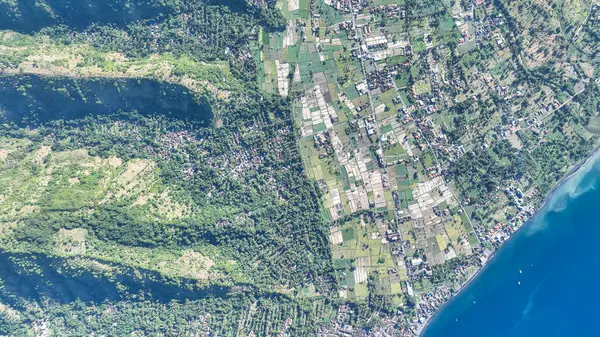 Bali 'deki Amed köyü üzerinde muhteşem bir hava manzarası. Bereketli yeşil tepeler canlı pirinç tarlalarına ve derin mavi denize akar. Doğu Bali 'nin dramatik sahil şeridini gözler önüne serer..