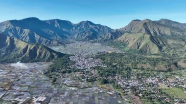 Yamalı pirinç tarlaları ve dramatik dağ sırtlarıyla Sembalun 'un hava manzarası. Bu bereketli vadi Rinjani maceralarına açılan kapıdır..