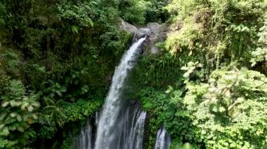 Tiu Kelep şelalesinin üst akıntısı dramatik bir düşüş yapmadan önce kayaların üzerinden yavaşça akar. Tropikal orman kristal berrak suyu doğal ortamda çerçeveler..