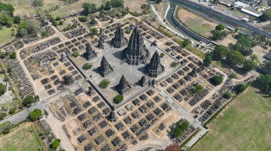 Görkemli Prambanan kompleksi engin bir arkeolojik alanın kalbinde duruyor, ikonik kuleleri gökyüzüne doğru uzanıyor dağınık tapınak kalıntıları ve yemyeşil alanlar arasında...