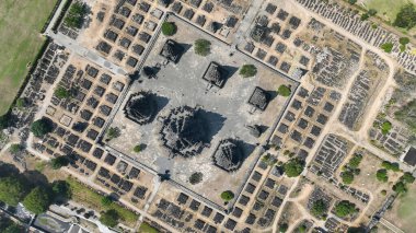 Nefes kesici bir hava manzarası, Java 'da dağınık taş kalıntıları ve yemyeşil ağaçlarla çevrili antik bir tapınak kompleksinin karmaşık planını ortaya koyuyor..