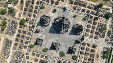 Yukarıdan gelen görkemli Prambanan Tapınağı, merkezi kulelerin karmaşık düzenini gösteriyor. Etrafı geometrik kalıntılarla çevrili ve Java 'nın göbeğindeki dağınık ağaçlarla çevrili..