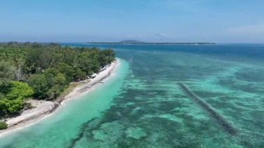 Palmiye ağaçları ve renkli şemsiyelerle kaplı tropik Pelangi plajı, kristal berrak sulardan ve nazik dalgalardan sadece birkaç adım uzakta..