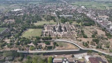 Yukarıdaki Prambanan Tapınağı kompleksi, yeşil parklar ve Endonezya 'nın merkez kenti Cava yakınlarındaki akan nehir tarafından çerçevelenmiş ikonik taş kulelerini ve geometrik kalıntılarını sergiliyor...