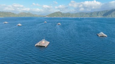 Bu sakin tropikal manzarayı tamamlayan sayısız bambu balıkçı salları, uzak tepelerle ışıl ışıl mavi sulara saçıldı..