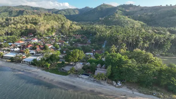 Lombok adasının manzaralı tepelerine kurulmuş, yoğun palmiye ağaçları ve canlı yeşilliklerle çevrili, huzurlu bir sahil toplumuna yakın çekim..