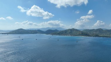 Kıyı tepeleri turkuaz suların üzerinde yükseliyor, sahil boyunca uzanan büyüleyici bir köy ve sahneyi noktalayan geleneksel bambu balıkçılık platformları, kara ve deniz arasındaki ahenge bir bakış sunuyor..