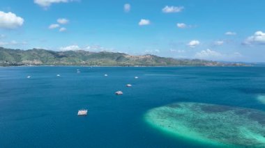 Sakin bir körfezin manzarası bambu balıkçı sallarıyla kaplı, yeşil tepeler ve berrak bir gökyüzünün altında huzurlu bir kıyı şeridi ile çevrili..