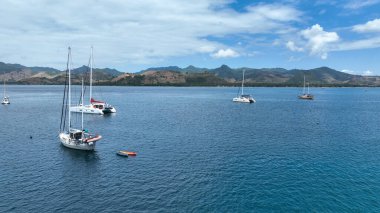 Zümrüt suları ve manzaralı tepelerle çevrili sakin bir koyda demirlemiş bir yat ve katamaran filosu. Yelkencilik ve ada keşfi için muhteşem bir yer..