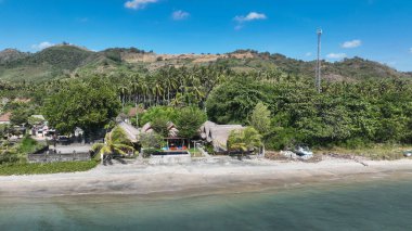 Deniz kenarındaki bungalovlar Hindistan cevizi palmiyeleri arasında yuva yapar. Yumuşak dalgaların açık mavi gökyüzünün altında kumlu sahille buluştuğu yerde huzurlu bir kaçış sunar..