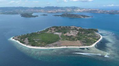 Yukarıdan Gili Katmanı, berrak suları, mercan sığlıkları ve parlak bir gökyüzünün altındaki Lombok adalarının manzaralı zeminiyle el değmemiş güzelliğini gösteriyor..