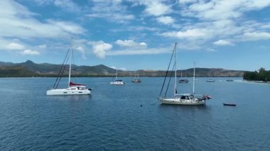 Zümrüt suları ve manzaralı tepelerle çevrili sakin bir koyda demirlemiş bir yat ve katamaran filosu. Yelkencilik ve ada keşfi için muhteşem bir yer..