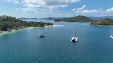 Gili Asahan yakınlarında demirlemiş yatları olan huzurlu bir körfez perspektifi. Avuç içi uzanan kıyılar ve zümrüt suları rüya gibi bir ada atmosferi sunar.