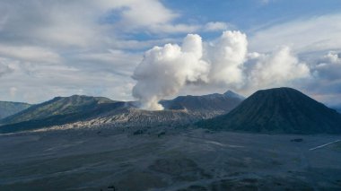 Doğu Java Endonezya 'daki Bromo Dağı' ndan yükselen volkanik duman bulutu engebeli araziye ve aşağıdaki geniş kalderaya karşı dramatik bir sahne oluşturuyor..