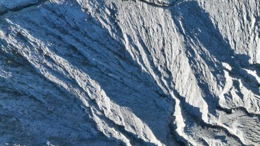 Yüzyılların rüzgâr ve külleriyle oyulmuş keskin volkanik çıkıntılar dramatik bir manzara yaratır. Engebeli doku, dünyayı şekillendiren doğal güçlerin ham gücünü ortaya koyuyor..