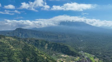 Bali 'nin kutsal volkanı Gunung Agung' un eteğindeki yemyeşil vadilerin ve uzak köylerin çarpıcı bir gökyüzünün altında görkemli bir şekilde yükselen nefes kesici manzarası..