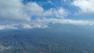 Bulutlar Gunung Agung 'un engin yamaçlarını silip süpürüyor. Güçlü varlığını kısmen örtüyor ve Bali manzarası üzerinde mistik bir atmosfer yaratıyor..