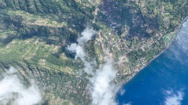 Göz kamaştırıcı bir tepeden aşağı manzara, Amed köyünün yeşil pirinç tarlalarının derin mavi denizle buluştuğu kıyı şeridini gözler önüne seriyor. Aşağıda süzülen bulutlar bu Bali cennetine rüya gibi bir dokunuş ekler..