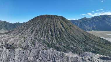 Görkemli Batok volkanik yamaçları açık mavi gökyüzüne doğru yükseliyor. Bu eski oluşumun her çizgi ve eğrisinde doğa sanatının varlığı ortaya çıkıyor..