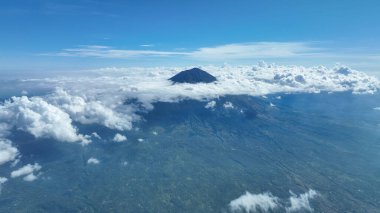 Agung Dağı 'nın güçlü silueti bulutların üzerinde süzülüyor gibi görünüyor etkileyici yamaçlarını ve volkanik şeklini ortaya çıkarıyor. Bu manzara, Bali 'nin en yüksek dağının hayranlık uyandıran güzelliğini yakalıyor..