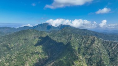 Yuvarlanan yeşil dağlar, kabarık bulutların zirveler boyunca sürüklendiği mesafeye kadar uzanıyor. Güneş ışığı ve gölgenin etkileşimi bu el değmemiş tropik cennetin vahşi güzelliğini gözler önüne seriyor..