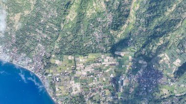 Bu yukarıdan aşağı bakış açısı Amed köyünün kalbini yakalıyor, pirinç tarlalarının parıldayan kıyı şeridi ile buluştuğu yer. Canlı manzara Bali 'nin doğal güzelliğini ve kırsal çekiciliğini sergiliyor..