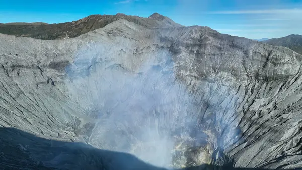 Yanan bir volkanın derinliklerine doğru nefes kesici bir manzara. Kraterlerin üzerinde dönen sis ve gölgenin dokuduğu yüzey..