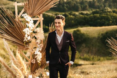 Genç yakışıklı sarışın damat düğün kemerinin yanında gelini bekliyor. Yüksek kalite fotoğraf