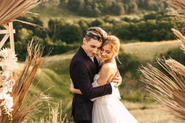 Birbirlerine aşık düğün çifti kemerin yanında sıkıca sarılıyorlar. Yüksek kalite fotoğraf