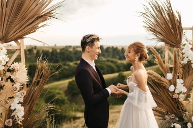 Yeni evliler düğün kemerindeki törende alyans taktılar. Yüksek kalite fotoğraf