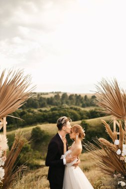 Düğün çifti kemerdeki törenden sonra yeni evliler öpüşür. Yüksek kalite fotoğraf