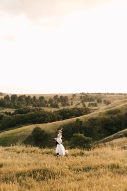 Yeni evliler birbirine aşık. Damat gelini kollarında tutuyor. Doğanın güzel manzarası. Yüksek kalite fotoğraf