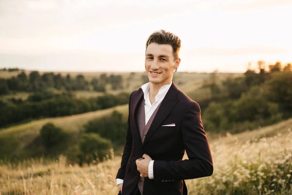 Handsome young groom in a suit posing in nature. High quality photo