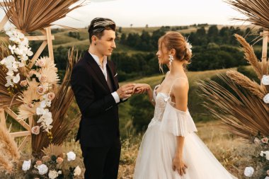 Yeni evliler düğün töreninde. Damat gelinin alyansını takar. Yüksek kalite fotoğraf