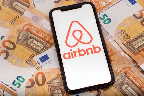 Paris, Fransa - 30 Kasım 2023: Airbnb uygulamalı akıllı telefon ve euro para Airbnb bir çevrimiçi pazar ve konukseverlik hizmetidir.